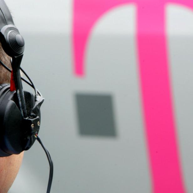 Ein Mann mit Kopfhörern steht vor einem Telekom-Logo.