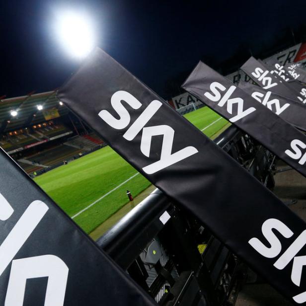 Mehrere Sky-Werbebanner stehen am Rande eines Fußballfeldes.