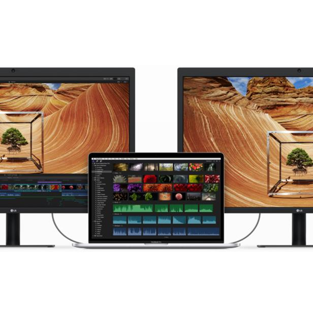 Zwei Monitore und ein Laptop zeigen eine Wüstenlandschaft mit einem Baum in einem Würfel.
