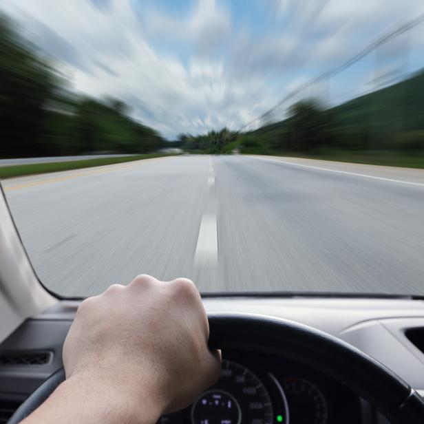 Eine Person fährt ein Auto auf einer Landstraße.