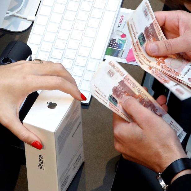 Eine Person bezahlt ein iPhone mit russischen Rubel-Scheinen.