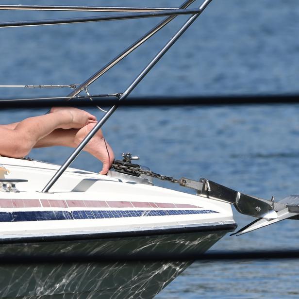 Eine Person entspannt sich auf dem Bug eines Bootes mit Blick auf das Wasser.