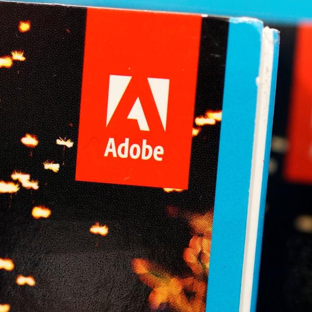 Das Adobe-Logo ist auf einem Buch mit einem Bild von Lichtern aufgedruckt.