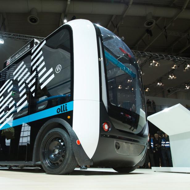 Der selbstfahrende Kleinbus „Olli“ wird auf einer Messe von Reportern fotografiert.