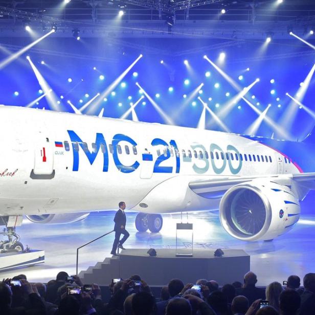 Ein MC-21-300 Flugzeug steht auf einer Bühne mit einem Mann, der die Treppe hochgeht.