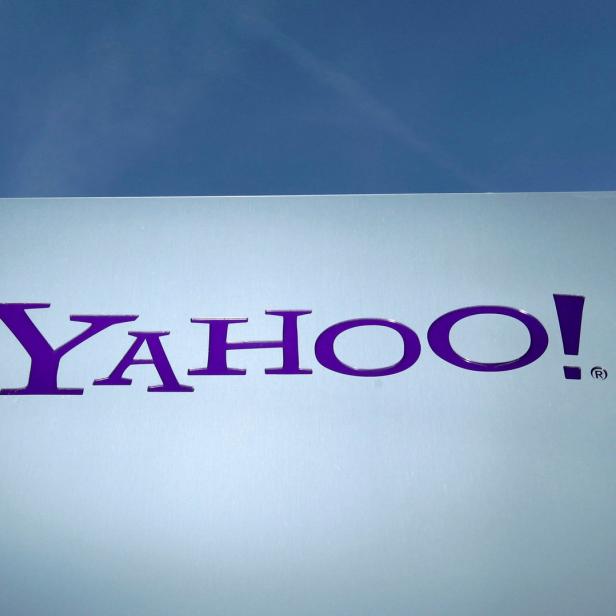 Das lila Yahoo!-Logo auf einem silbernen Schild vor blauem Himmel.