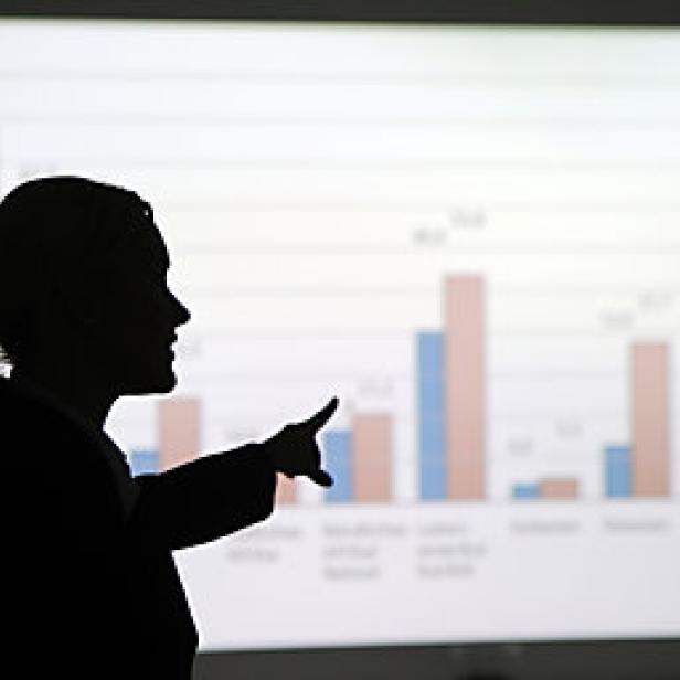 Die Silhouette einer Frau, die auf eine Grafik mit Balkendiagrammen zeigt.