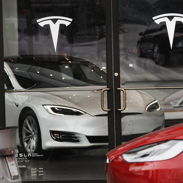 Mehrere Tesla-Fahrzeuge stehen vor einem Tesla-Showroom.