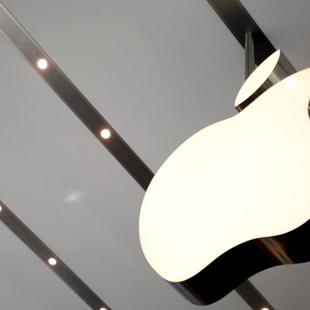 Das Apple-Logo hängt an einer Decke mit eingelassenen Strahlern.
