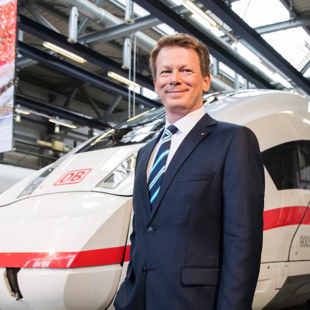 Ein Mann im Anzug steht vor einem ICE der Deutschen Bahn.
