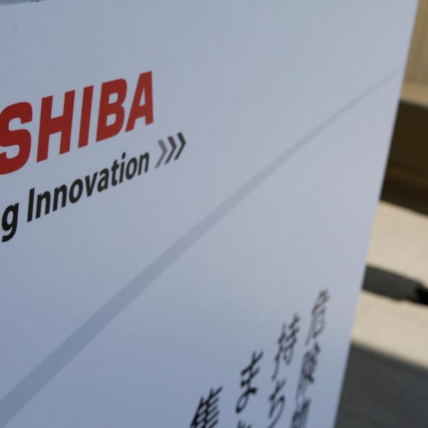 Das Toshiba-Logo mit dem Slogan „Leading Innovation“ vor einem vorbeigehenden Mann.