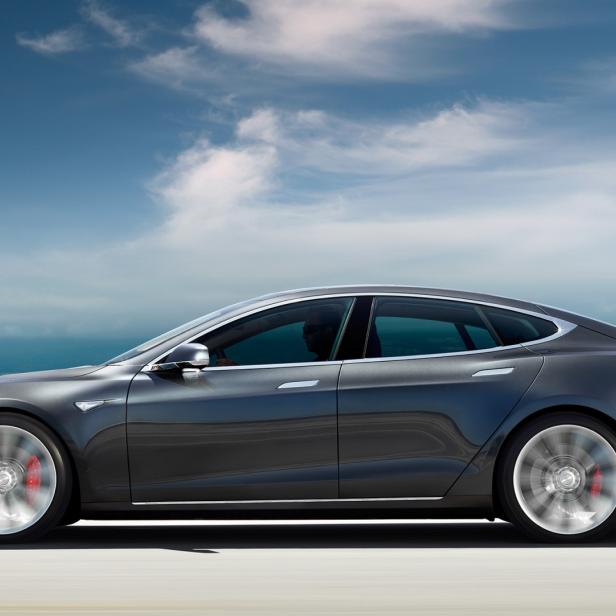Ein graues Tesla Model S fährt auf einer Küstenstraße.