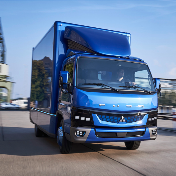 Ein blauer Fuso eCanter Elektro-Lkw fährt auf einer Straße.