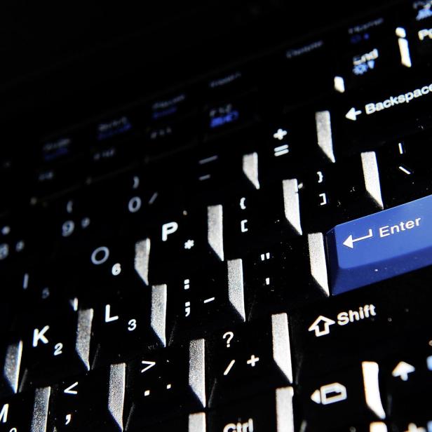 Nahaufnahme einer schwarzen Laptop-Tastatur mit einer blauen Enter-Taste.