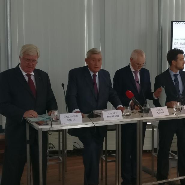 Mehrere Personen, darunter Hannes Androsch, stehen bei einer Bilanz-Pressekonferenz hinter einem Tisch.