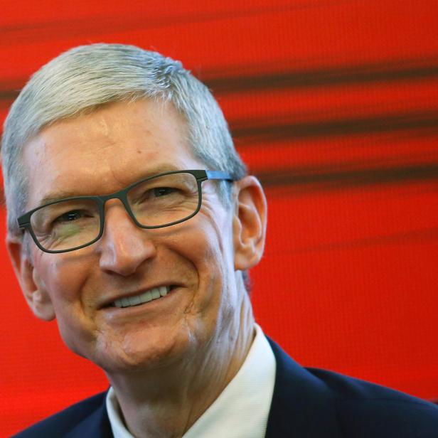Tim Cook, der CEO von Apple, lächelt vor einem roten Hintergrund.