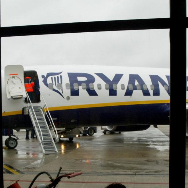 Ein Ryanair-Flugzeug steht am Flughafen, während Arbeiter auf dem Vorfeld tätig sind.