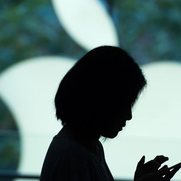 Die Silhouette einer Frau, die auf ihr Smartphone schaut.