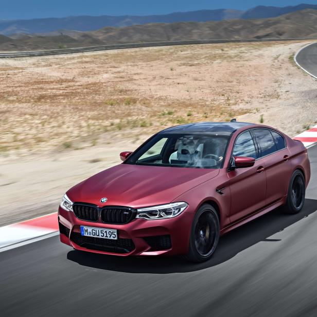 Ein rotbrauner BMW M5 fährt auf einer Rennstrecke.