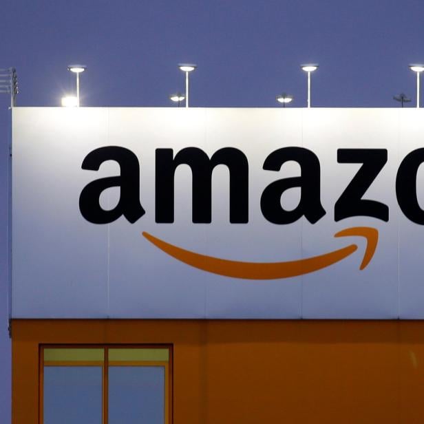 Ein großes Amazon-Logo an einem Gebäude bei Dämmerung.