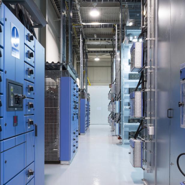 Ein langer Gang mit blauen Schaltschränken und silbernen Geräten in einem Rechenzentrum.