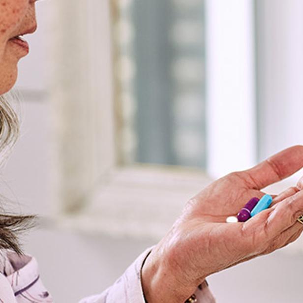 Eine Frau hält verschiedene Pillen in ihrer Hand.