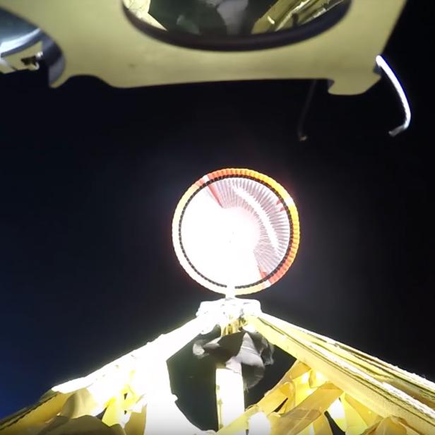 Ein Fallschirm öffnet sich vor einem dunklen Himmel.