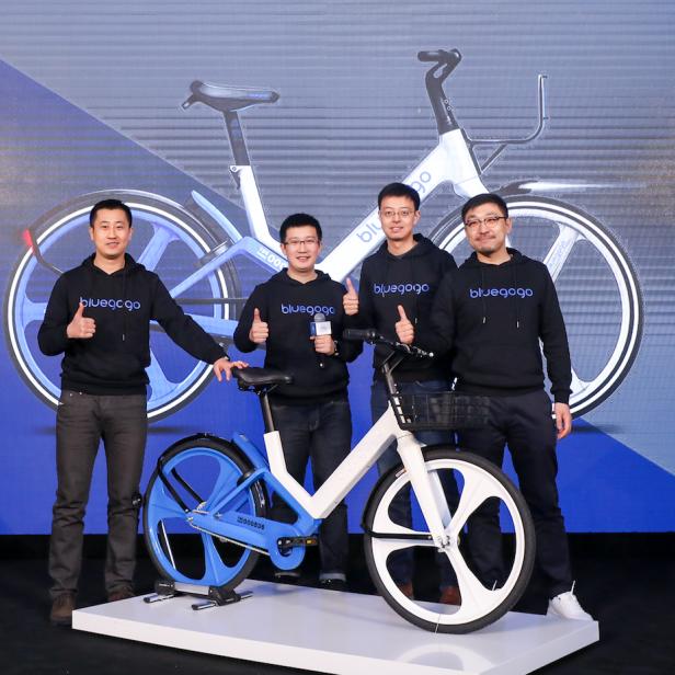Vier Männer posieren mit einem Bluegogo-Fahrrad für ein Foto.