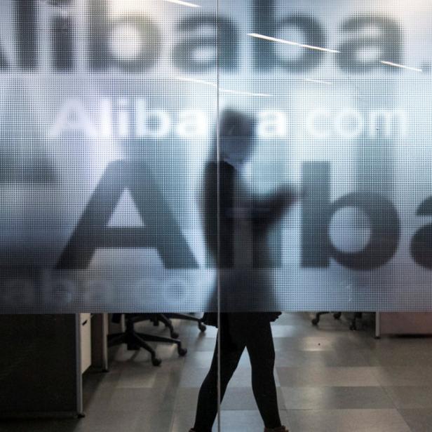 Eine Person geht an einer Glastür mit dem Alibaba-Logo vorbei.