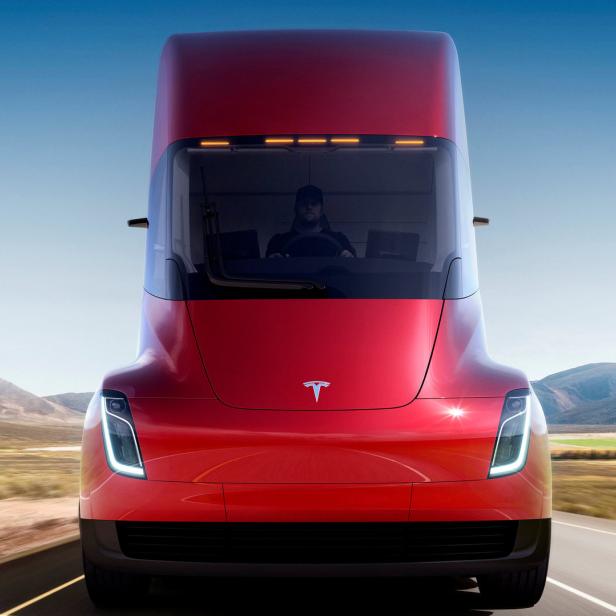 Ein roter Tesla Semi fährt auf einer Landstraße.