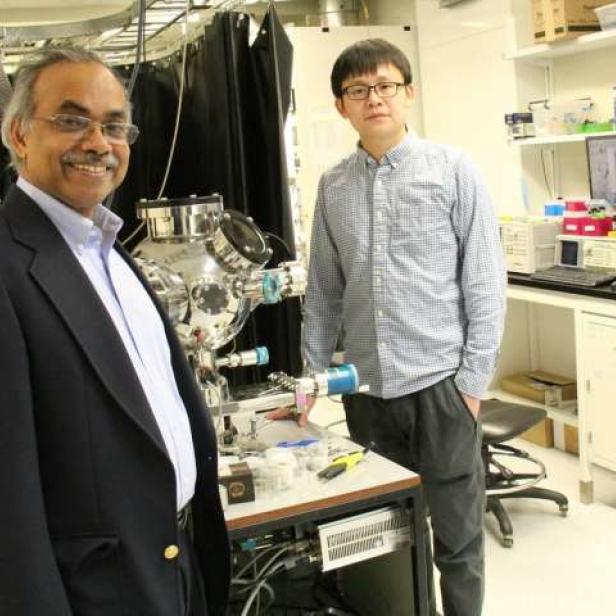 Zwei Männer stehen in einem Labor vor einer wissenschaftlichen Apparatur.