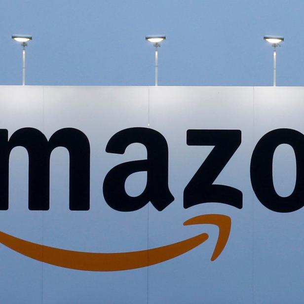Das Amazon-Logo auf einer großen Werbetafel unter mehreren Lampen.