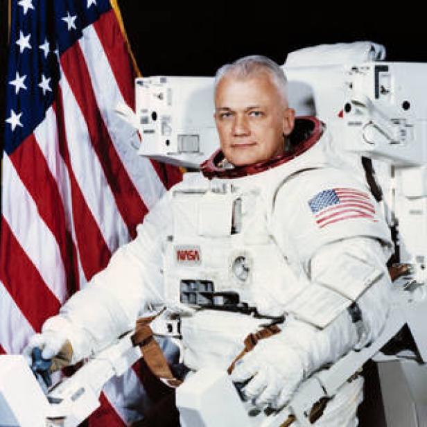 Astronaut in einem Raumanzug vor der amerikanischen Flagge.