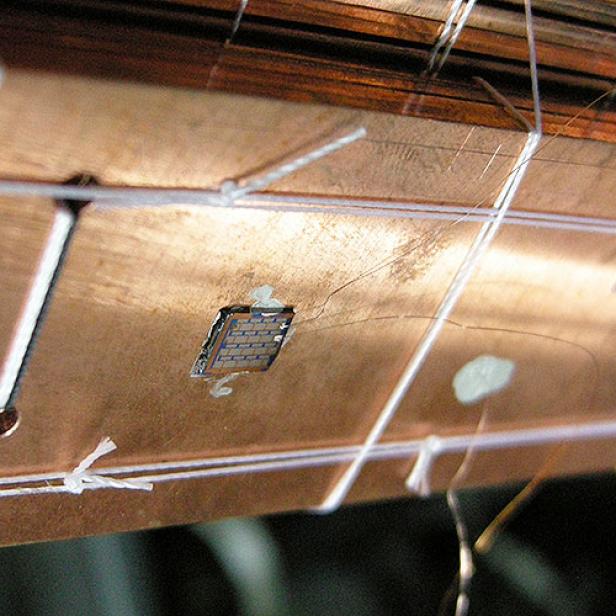 Ein Chip ist mit feinen Drähten auf einer Kupferoberfläche befestigt.
