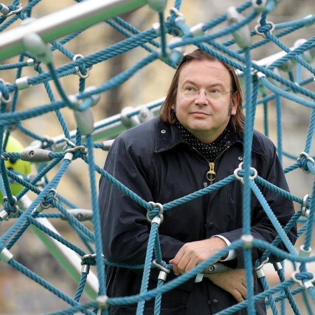 Ein Mann mit Brille steht in einem Klettergerüst aus Seilen und Metall.