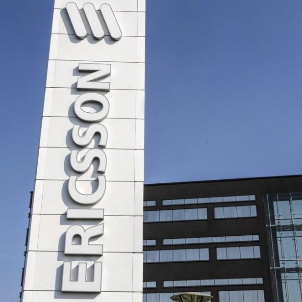 Das Ericsson-Logo vor einem Bürogebäude unter blauem Himmel.