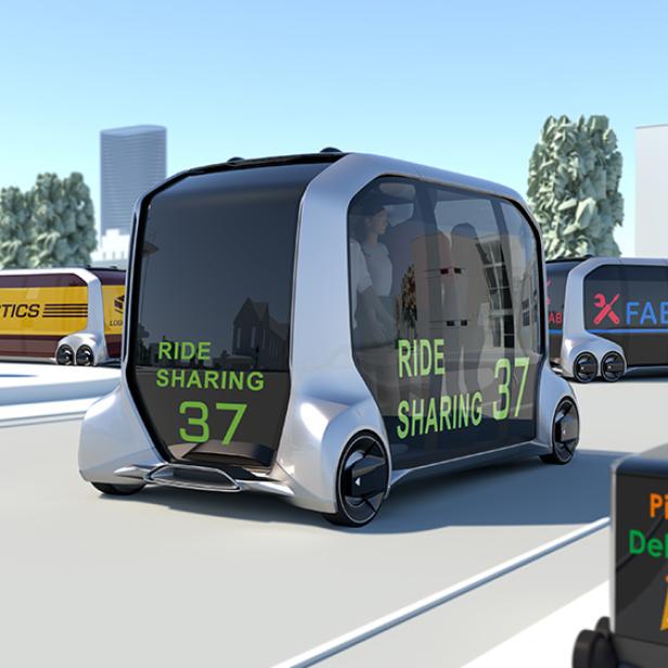 Mehrere autonome Fahrzeuge, darunter eines für Mitfahrgelegenheiten und eines für Pizzalieferungen, sind auf einer Straße unterwegs.