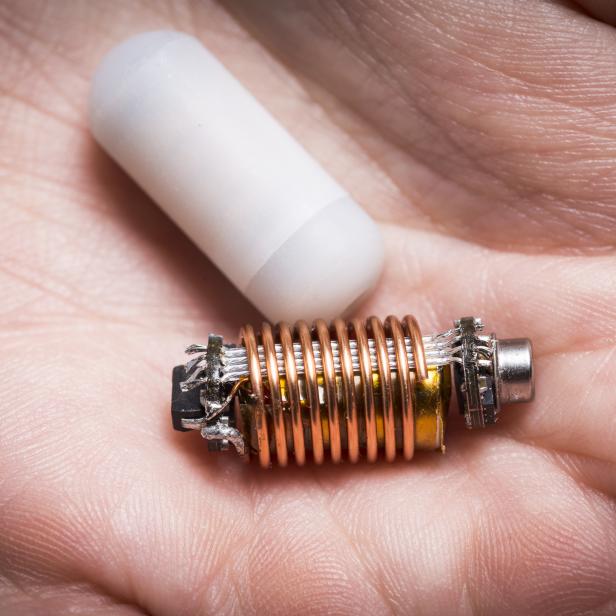 Ein RFID-Chip und eine Spule liegen auf einer Handfläche.