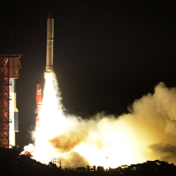 Eine Rakete startet bei Nacht mit einer großen Rauchwolke.