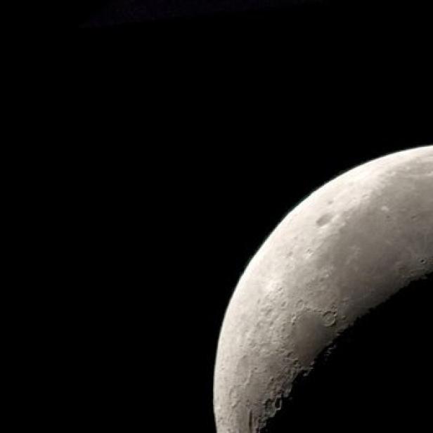 Ein Satellit umkreist einen teilweise beleuchteten Mond vor schwarzem Hintergrund.