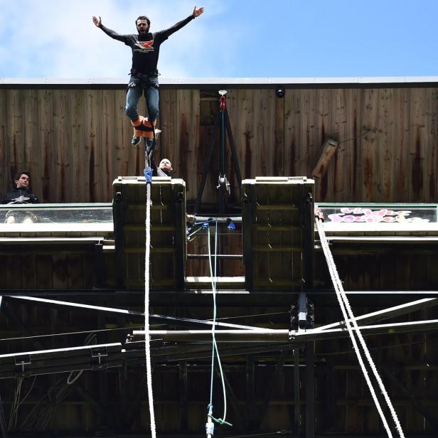 Ein Mann springt mit einem Bungeeseil von einer hohen Plattform.