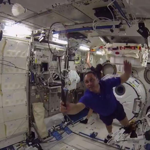 Ein Astronaut schwebt in der Internationalen Raumstation und winkt in die Kamera.