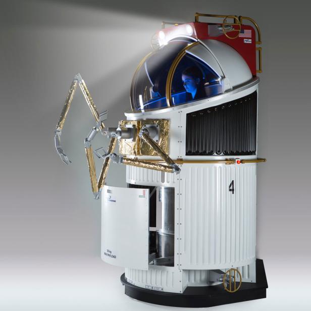 Eine Astronautin sitzt in einem Mondsimulationsgerät mit Roboterarmen.