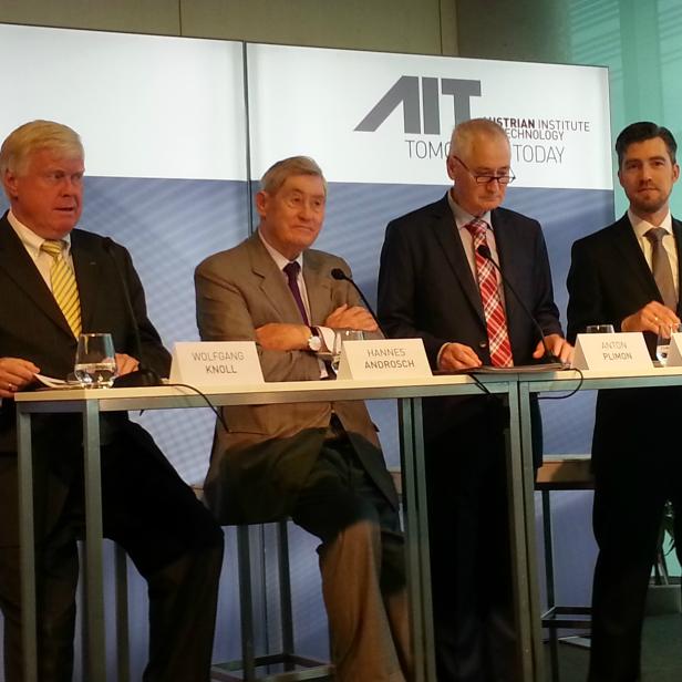 Vier Männer in Anzügen stehen hinter einem Tisch mit Namensschildern des AIT Austrian Institute of Technology.