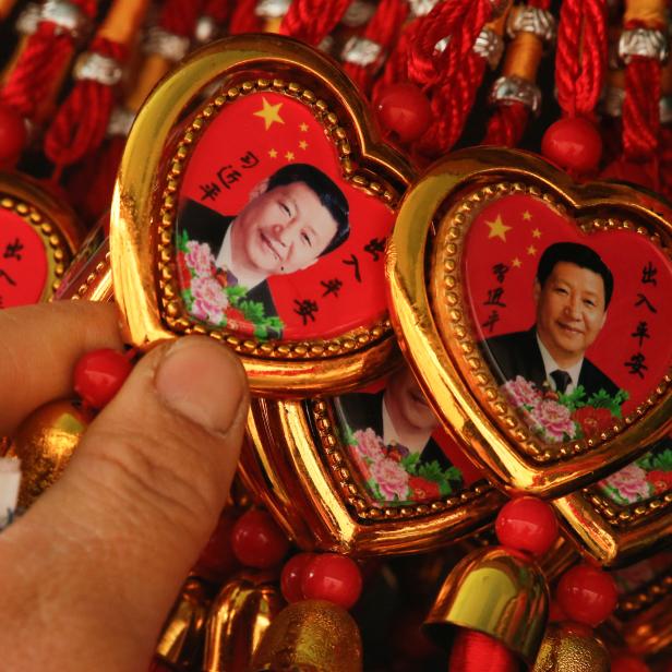 A woman picks a souvenir necklace with a portrait of Chinese President Xi Jinping from a selection that also includes necklaces featuring late Chinese Chairman Mao Zedong at a stall in Beijing