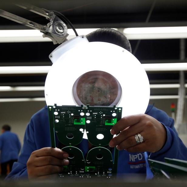 An employee inspects a printed circuit board at the assembly line of a factory that exports to the U.S. in Ciudad Juarez