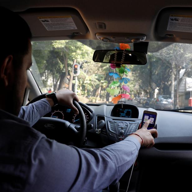 Uber driver checks the route on a mobile phone inside his car in Mexico City