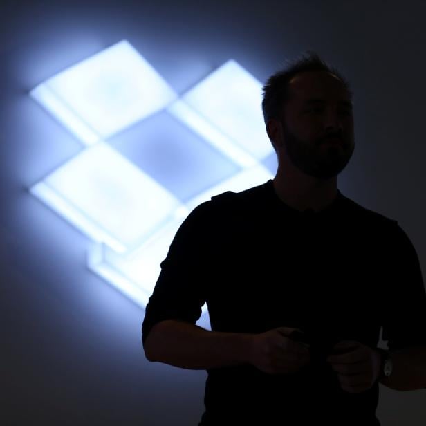 Drew Houston, Chief Executive Officer and founder of Dropbox, stands in front of the company's logo at an announcement event in San Francisco