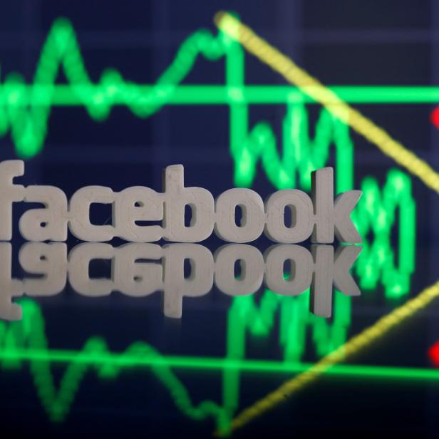 A 3D-printed Facebook logo is seen in front of displayed stock graph