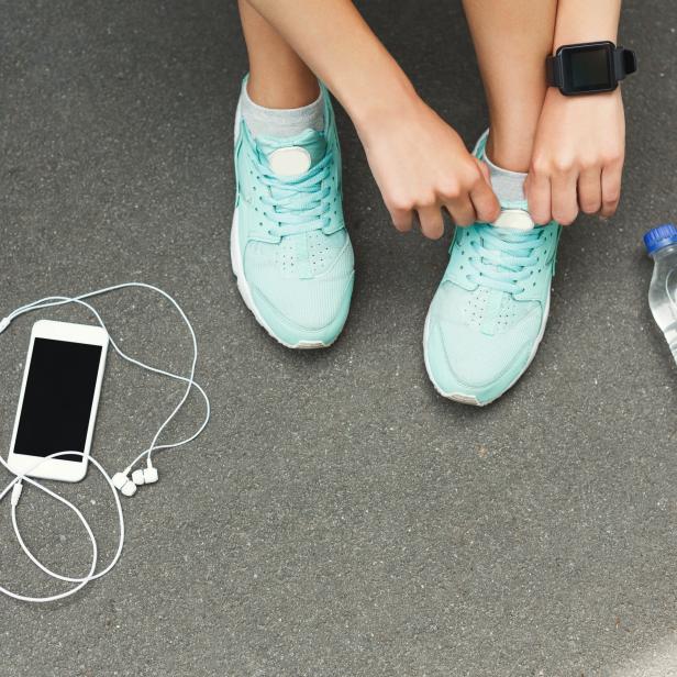 Woman tying shoes laces before running top view